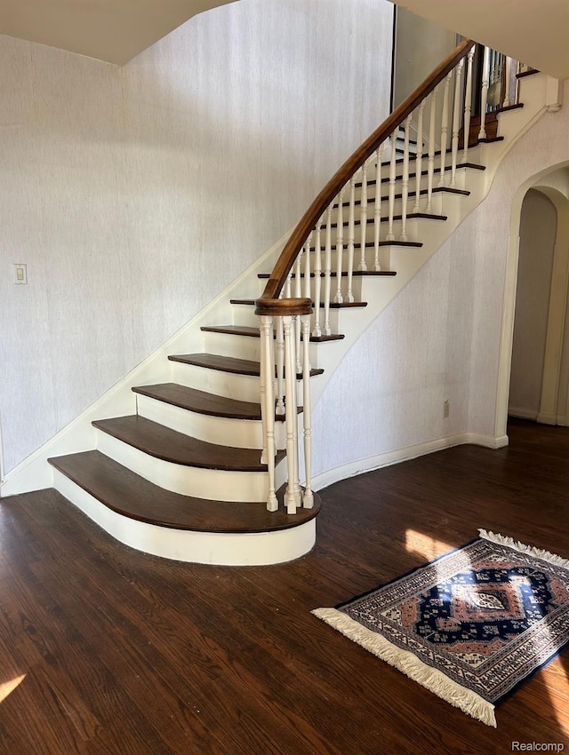 25490 E River Rd, Grosse Ile, MI 48138 - stairway with arched walkways, wood finished floors, baseboards, and wallpapered walls