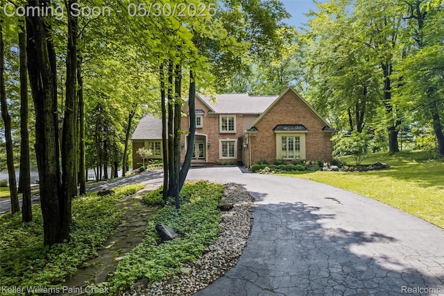 3120 Pond Rd, Leonard, MI 48367 - colonial house with brick siding, driveway, and a front lawn