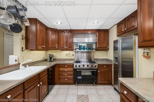3120 Pond Rd, Leonard, MI 48367 - kitchen with stainless steel appliances, wall chimney range hood, recessed lighting, light tile patterned floors, and a sink
