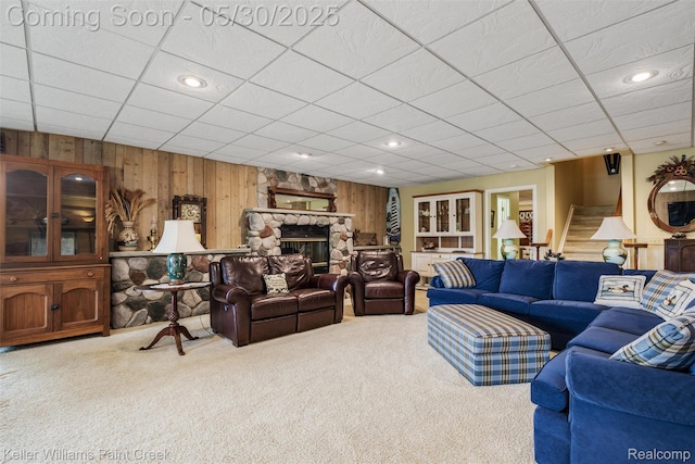 3120 Pond Rd, Leonard, MI 48367 - living area featuring carpet, wood walls, stairway, a fireplace, and a drop ceiling