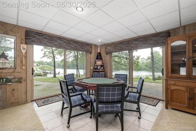 3120 Pond Rd, Leonard, MI 48367 - dining room featuring wood walls, a paneled ceiling, plenty of natural light, a water view, and light tile patterned floors