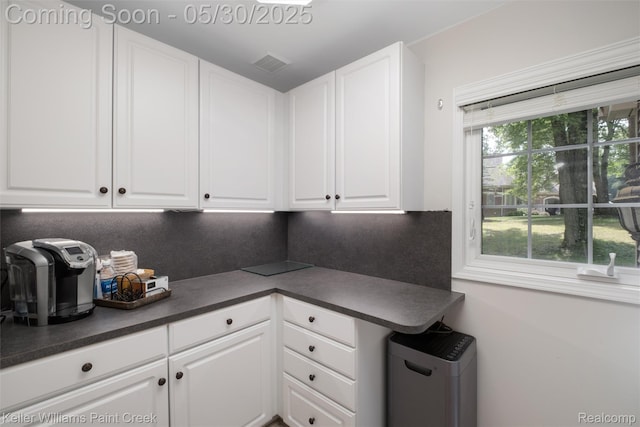 3120 Pond Rd, Leonard, MI 48367 - kitchen featuring dark countertops, white cabinetry, tasteful backsplash, and refrigerator