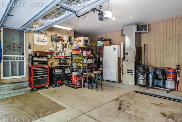 3120 Pond Rd, Leonard, MI 48367 - garage featuring wood walls, freestanding refrigerator, a garage door opener, and a workshop area