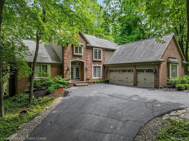 3120 Pond Rd, Leonard, MI 48367 - view of front facade featuring a garage, driveway, brick siding, and a shingled roof