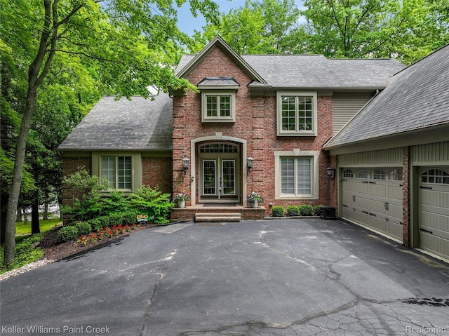 3120 Pond Rd, Leonard, MI 48367 - view of front of house with french doors, a shingled roof, asphalt driveway, a garage, and brick siding