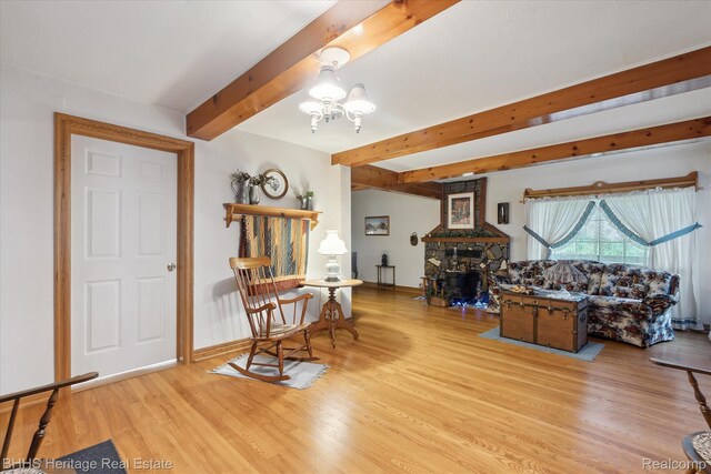 301 N Church St, Byron, MI 48418 - living room featuring a chandelier, beamed ceiling, wood finished floors, a stone fireplace, and baseboards