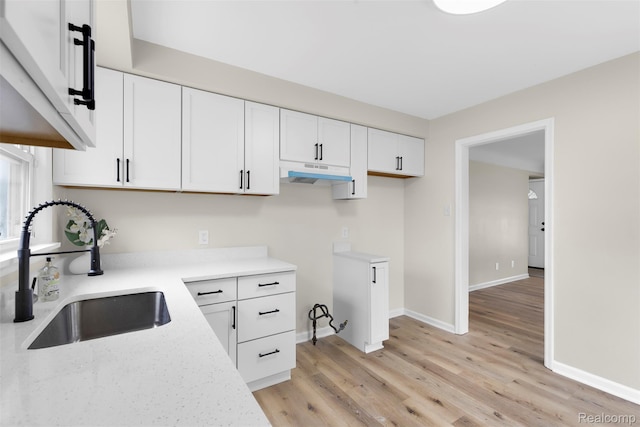1621 Fairbairn St, Dearborn, MI 48141 - kitchen featuring under cabinet range hood, white cabinets, light wood-type flooring, and light stone counters