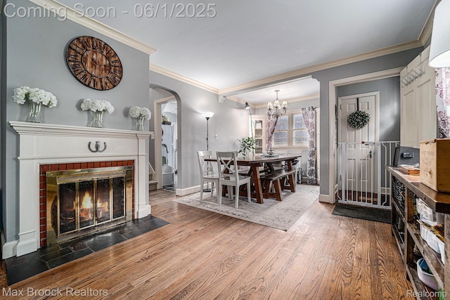 1312 Catalpa Dr, Royal Oak, MI 48067 - dining space with baseboards, a brick fireplace, arched walkways, wood finished floors, and crown molding
