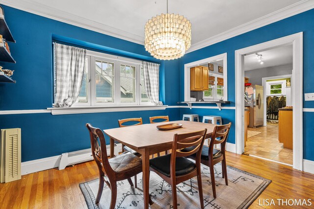 639 College Ave NE, Grand Rapids, MI 49503 - dining room with a chandelier, crown molding, light wood-style flooring, baseboards, and a baseboard heating unit