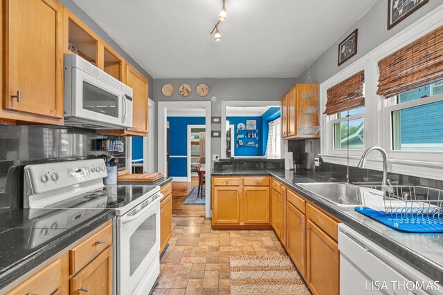 639 College Ave NE, Grand Rapids, MI 49503 - kitchen featuring white appliances, a sink, light stone finish floors, dark countertops, and tasteful backsplash