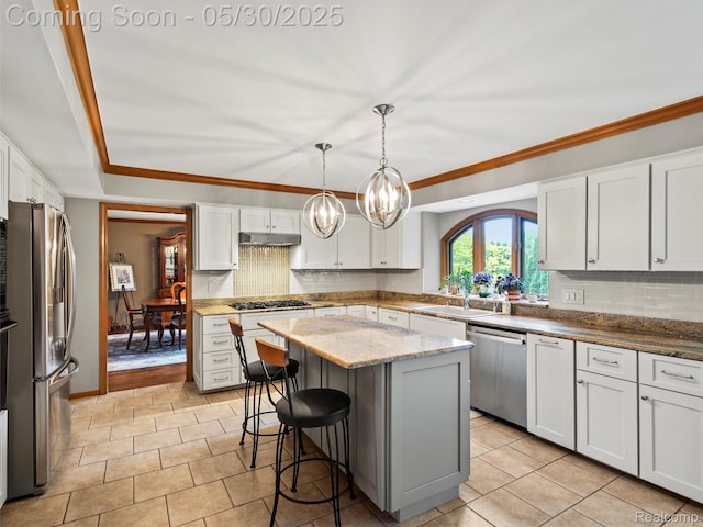 1552 Pebble Creek Dr, Rochester, MI 48307 - kitchen featuring stainless steel appliances, under cabinet range hood, tasteful backsplash, a center island, and ornamental molding