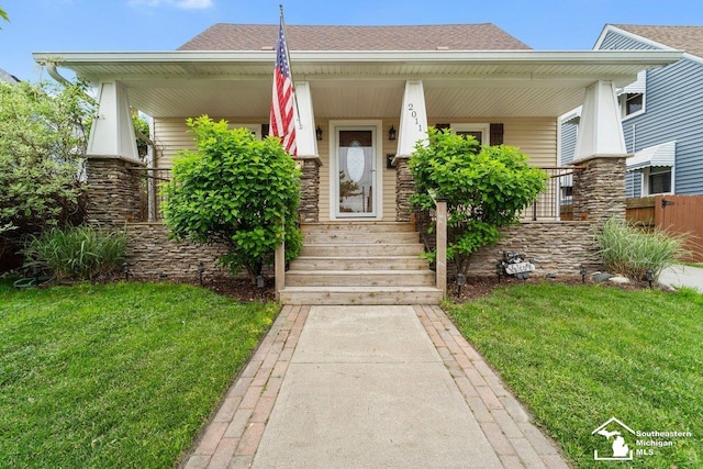 2011 5th St, Wyandotte, MI 48192 - view of front facade featuring a porch, a shingled roof, a front lawn, and stone siding