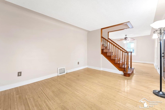 2011 5th St, Wyandotte, MI 48192 - unfurnished living room featuring stairs, light wood-style floors, baseboards, and a ceiling fan