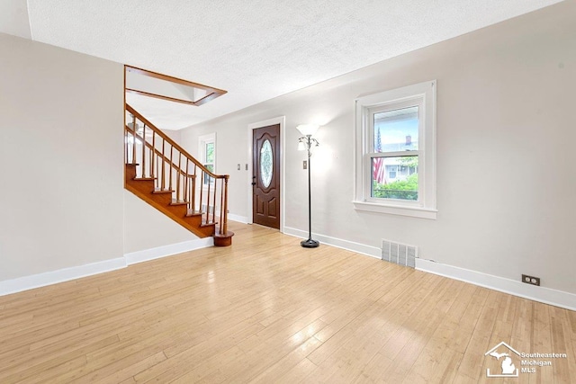 2011 5th St, Wyandotte, MI 48192 - entryway with baseboards, a textured ceiling, stairway, and light wood finished floors
