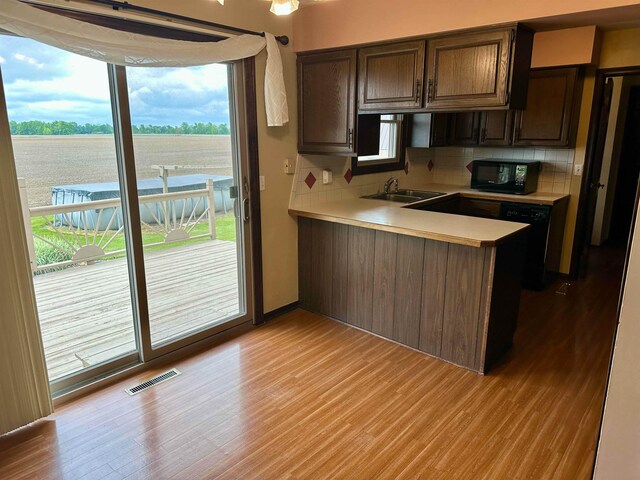 19379 Lincoln Rd, New Lothrop, MI 48460 - kitchen featuring black appliances, light countertops, tasteful backsplash, light wood finished floors, and a peninsula