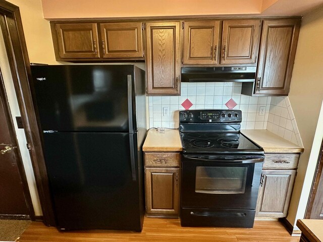 19379 Lincoln Rd, New Lothrop, MI 48460 - kitchen featuring black appliances, under cabinet range hood, light countertops, and light wood-type flooring
