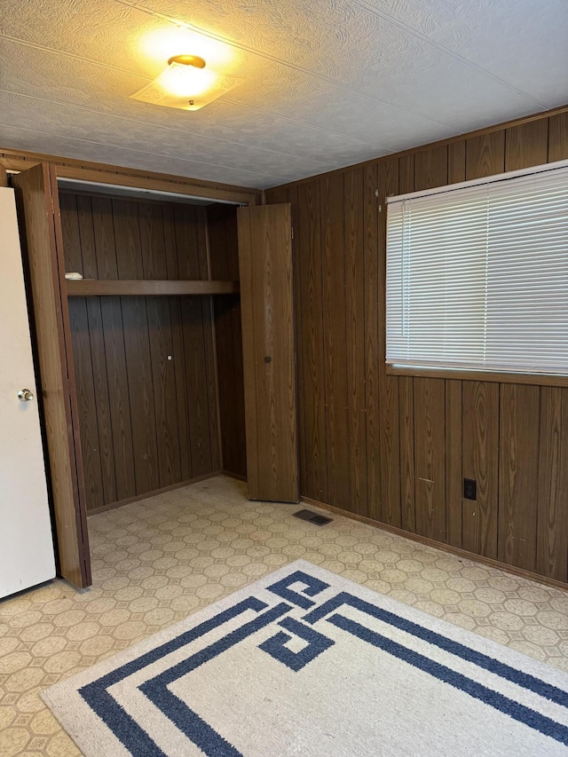 1235 Princeton St, Manistee, MI 49660 - unfurnished bedroom featuring a closet, wooden walls, and tile patterned floors