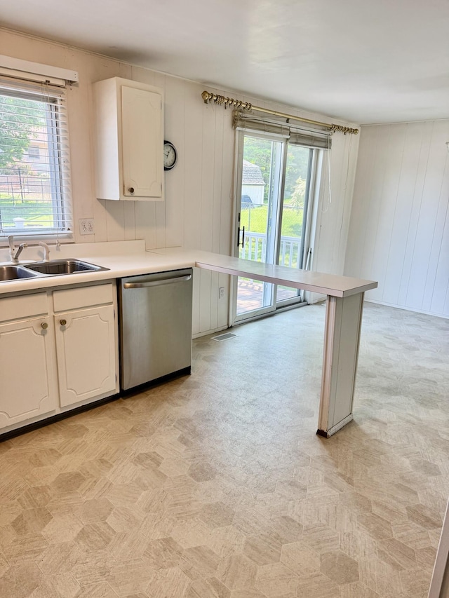 1235 Princeton St, Manistee, MI 49660 - kitchen with dishwasher, a sink, light countertops, white cabinets, and light colored carpet