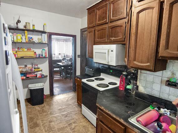 2041 Atkinson St, Detroit, MI 48206 - kitchen with white appliances, tasteful backsplash, a sink, and dark countertops
