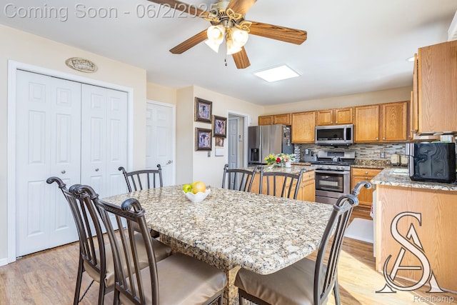6420 Crestview Dr, Holly, MI 48442 - kitchen with appliances with stainless steel finishes, a center island, light wood-style floors, a ceiling fan, and backsplash