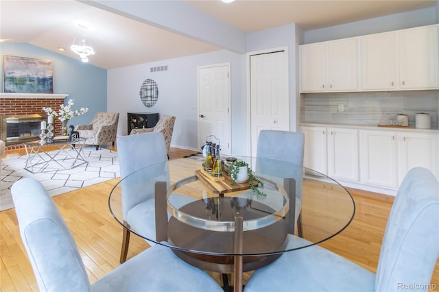 2864 Mystic Dr, Ann Arbor, MI 48103 - dining area with light wood-type flooring, a fireplace, and vaulted ceiling