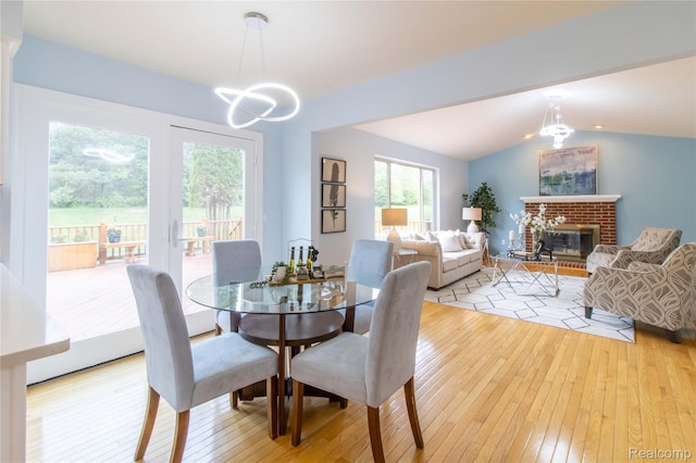 2864 Mystic Dr, Ann Arbor, MI 48103 - dining space with light wood-type flooring, a chandelier, vaulted ceiling, and a fireplace