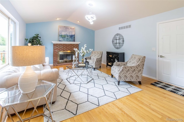 2864 Mystic Dr, Ann Arbor, MI 48103 - living room with wood finished floors, vaulted ceiling, a brick fireplace, a chandelier, and baseboards