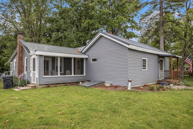 510 Cedar St, Paw Paw, MI 49079 - rear view of property featuring a chimney, a yard, metal roof, and a sunroom