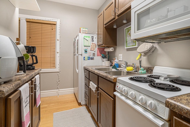128 S Main St, Lawton, MI 49065 - kitchen featuring white appliances, a sink, light wood-style floors, and baseboards