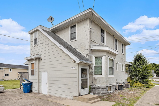 128 S Main St, Lawton, MI 49065 - view of front of home featuring central air condition unit, stucco siding, and a shingled roof