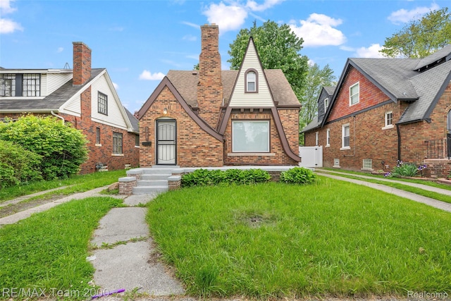 5935 Devonshire Rd, Dearborn, MI 48224 - tudor-style house with brick siding, a front lawn, and a shingled roof