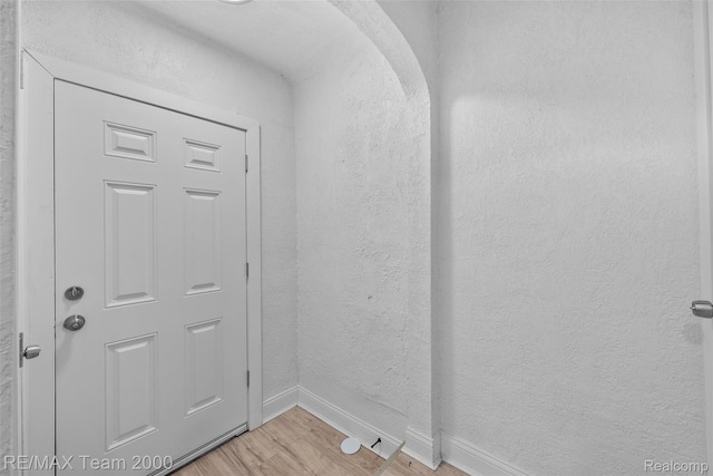 5935 Devonshire Rd, Dearborn, MI 48224 - doorway with light wood-type flooring, baseboards, a textured wall, and arched walkways