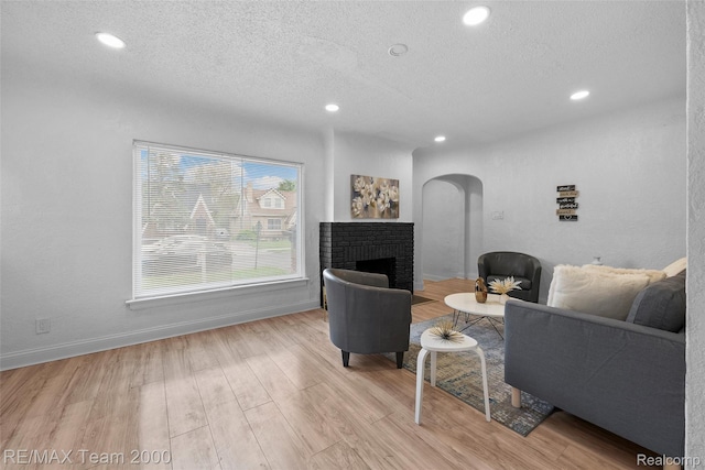 5935 Devonshire Rd, Dearborn, MI 48224 - living room with arched walkways, a textured ceiling, recessed lighting, a brick fireplace, and wood finished floors
