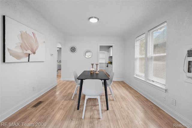 5935 Devonshire Rd, Dearborn, MI 48224 - dining area with arched walkways, light wood-type flooring, a textured ceiling, and baseboards