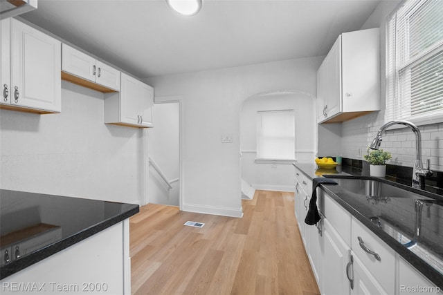 5935 Devonshire Rd, Dearborn, MI 48224 - kitchen with a sink, decorative backsplash, white cabinetry, arched walkways, and light wood-type flooring