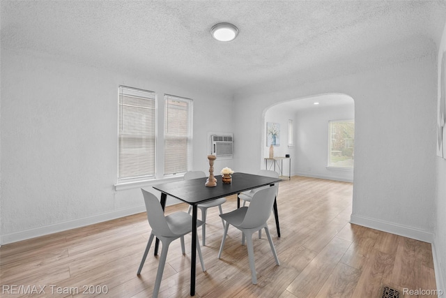 5935 Devonshire Rd, Dearborn, MI 48224 - dining area with arched walkways, a textured ceiling, light wood-style flooring, baseboards, and an AC wall unit