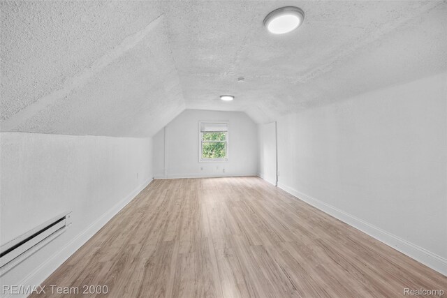 5935 Devonshire Rd, Dearborn, MI 48224 - additional living space featuring a textured ceiling, baseboard heating, wood finished floors, vaulted ceiling, and baseboards