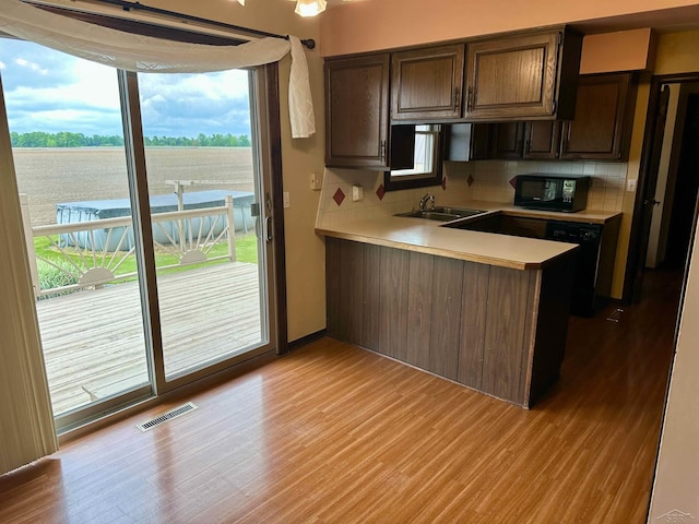 19379 Lincoln Rd, New Lothrop, MI 48460 - kitchen with black appliances, light countertops, tasteful backsplash, light wood-style floors, and a peninsula