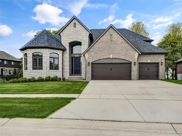 50011 Anita Way N, Macomb, MI 48044 - french provincial home with a garage, concrete driveway, stone siding, a front yard, and a shingled roof