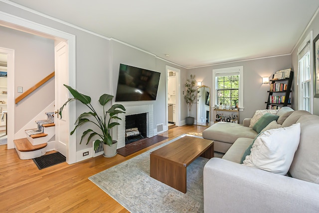 1512 Brooklyn Ave, Ann Arbor, MI 48104 - living area with light wood-style floors, stairs, a brick fireplace, and ornamental molding