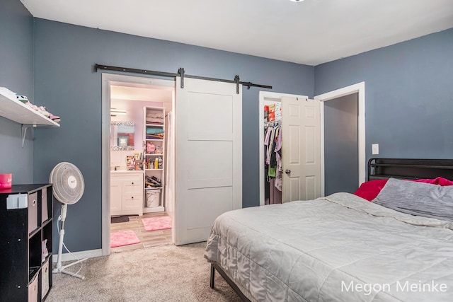 7813 River St, Belding, MI 48809 - bedroom featuring light colored carpet, a barn door, ensuite bath, baseboards, and a closet