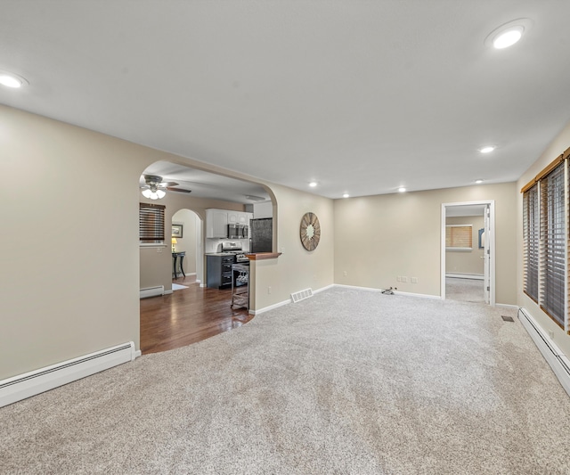 4841 Pear Way, Farwell, MI 48622 - unfurnished living room with carpet flooring, arched walkways, baseboard heating, recessed lighting, and baseboards
