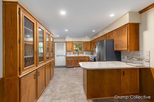 2870 S Wentward Ct, Hudsonville, MI 49426 - kitchen with appliances with stainless steel finishes, a peninsula, brown cabinets, tasteful backsplash, and recessed lighting