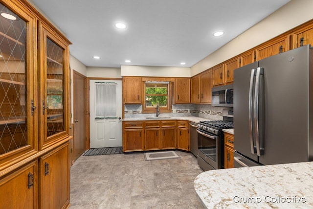2870 S Wentward Ct, Hudsonville, MI 49426 - kitchen with stainless steel appliances, a sink, brown cabinetry, light countertops, and decorative backsplash