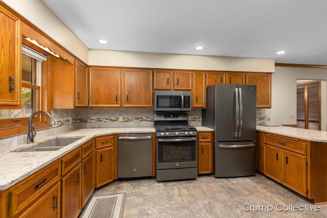 2870 S Wentward Ct, Hudsonville, MI 49426 - kitchen featuring appliances with stainless steel finishes, a sink, brown cabinets, tasteful backsplash, and light stone counters