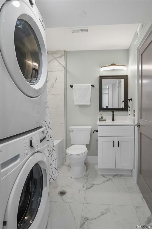 344 Main St Unit 300, Milford, MI 48381 - bathroom with stacked washer / drying machine, marble finish floors, toilet, and vanity