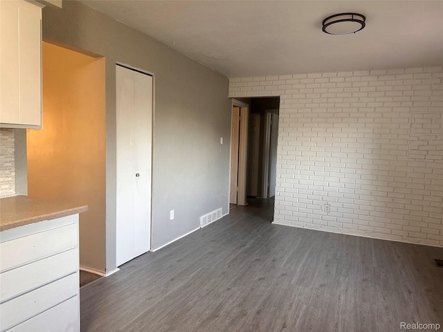 26304 Patricia Ave, Sterling Heights, MI 48091 - unfurnished living room with dark wood finished floors, baseboards, and brick wall