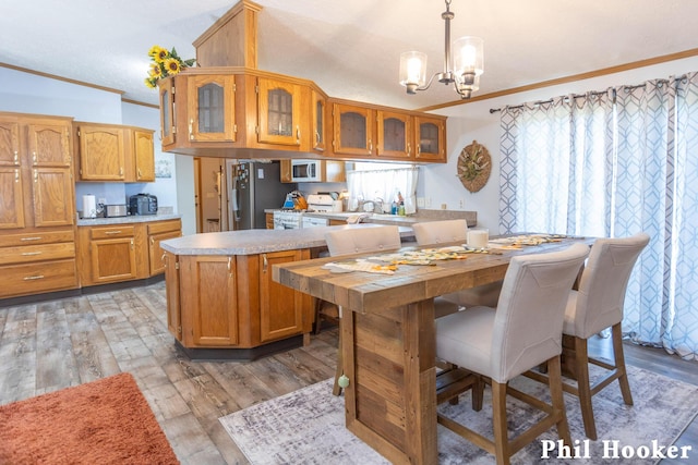 105 Penny Ln, Stanton, MI 48888 - kitchen with crown molding, light countertops, brown cabinetry, a chandelier, and light wood-type flooring