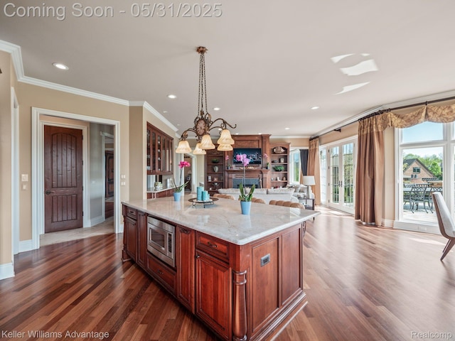 20971 Pomino Dr, Northville, MI 48167 - kitchen with stainless steel microwave, open floor plan, crown molding, a chandelier, and glass insert cabinets
