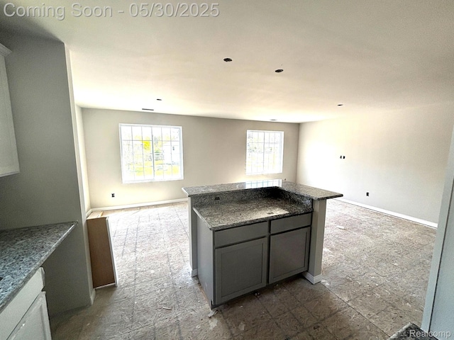 120 Whispering Pines Dr, Fenton, MI 48430 - kitchen with a kitchen island, stone countertops, open floor plan, and baseboards
